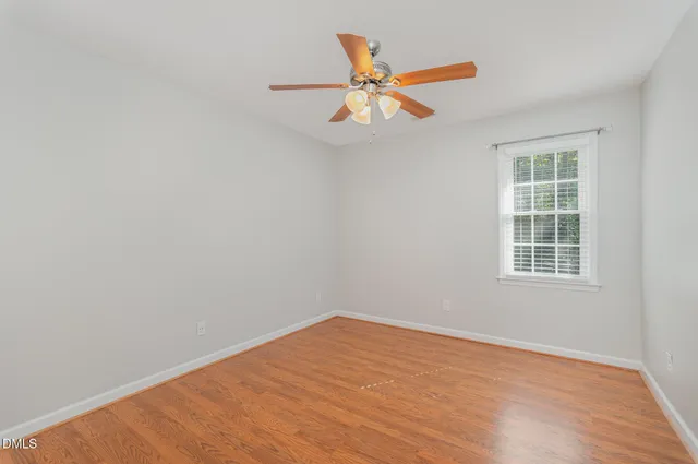 an empty room with a window and ceiling fan