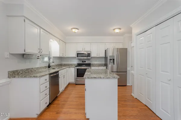 a kitchen with stainless steel appliances granite countertop a stove top oven a refrigerator and white cabinets