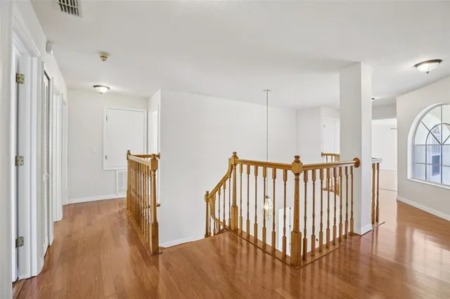 a view of an empty room with wooden floor and a ceiling fan
