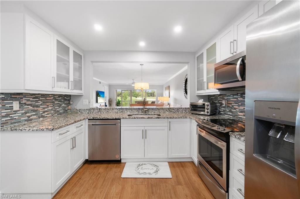 4572 Andover Way, Unit C105 Naples, FL 34112 - Photo 12 of 50 a kitchen with stainless steel appliances kitchen island granite countertop a stove a sink and a microwave
