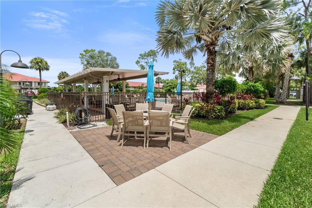4572 Andover Way, Unit C105 Naples, FL 34112 - Photo 34 of 50 a view of a patio with a table and chairs under an umbrella