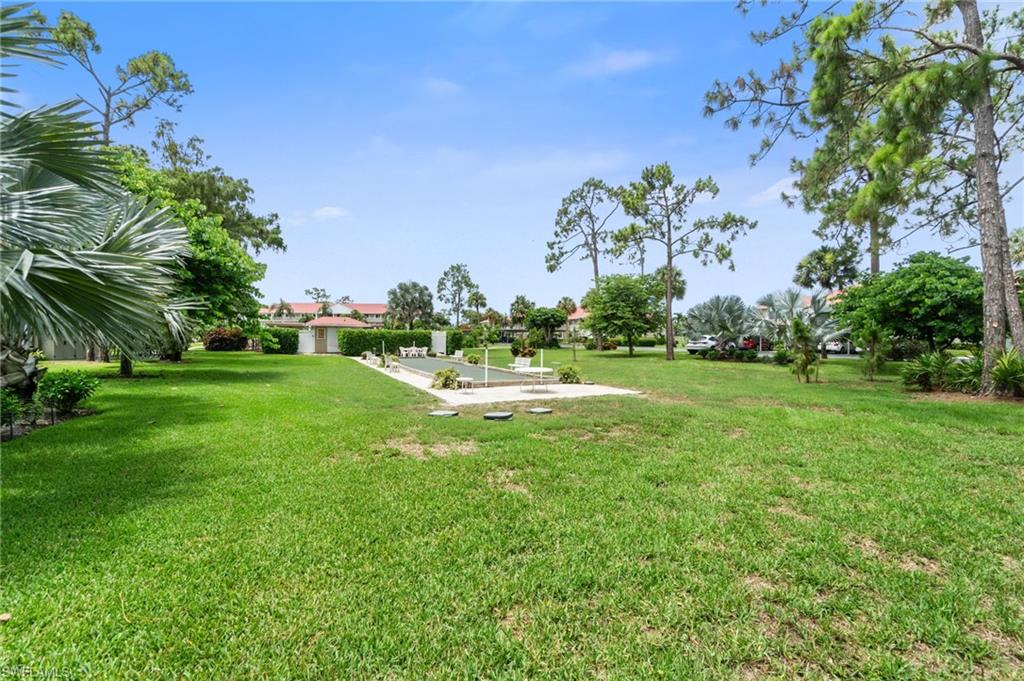 4572 Andover Way, Unit C105 Naples, FL 34112 - Photo 45 of 50 a view of a garden with a building in the background