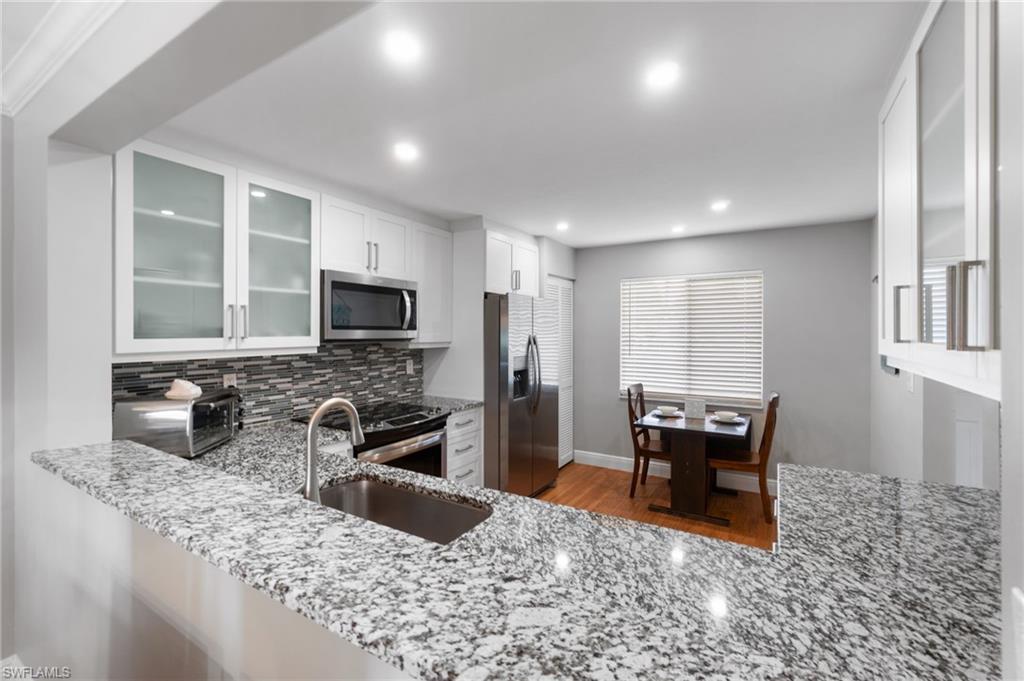 4572 Andover Way, Unit C105 Naples, FL 34112 - Photo 8 of 50 a kitchen with stainless steel appliances granite countertop a sink stove and refrigerator