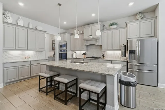 a kitchen with stainless steel appliances granite countertop a table chairs refrigerator and microwave