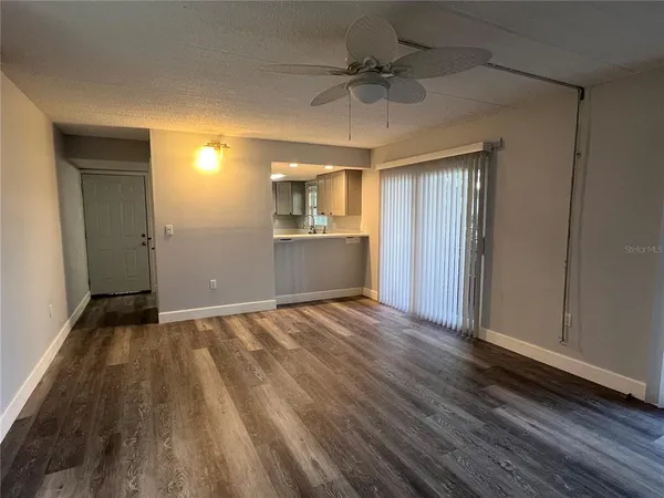 a view of empty room with wooden floor and ceiling fan