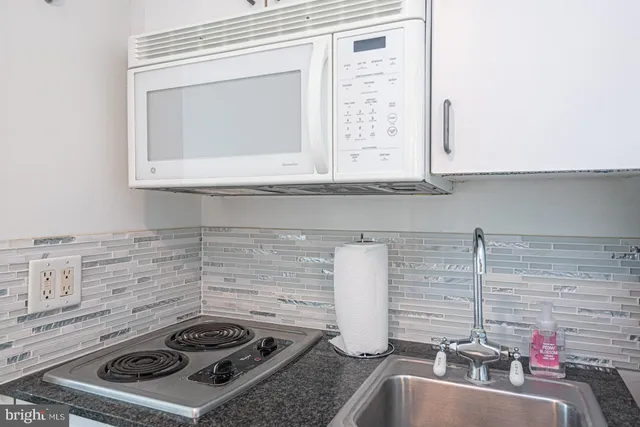 a kitchen with granite countertop a sink stove and cabinets