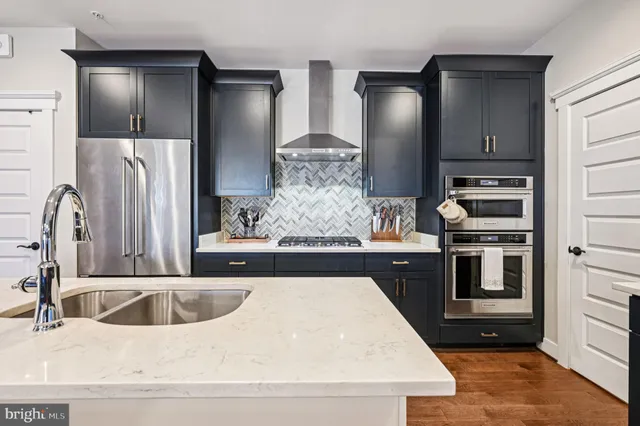 a kitchen with stainless steel appliances kitchen island granite countertop a refrigerator a sink and wooden cabinets