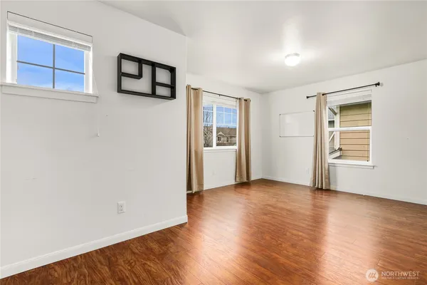 a view of an empty room with window and wooden floor