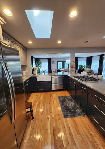 a large kitchen with stainless steel appliances wooden floor and a counter top space