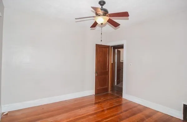 an empty room with wooden floor fan and a ceiling fan