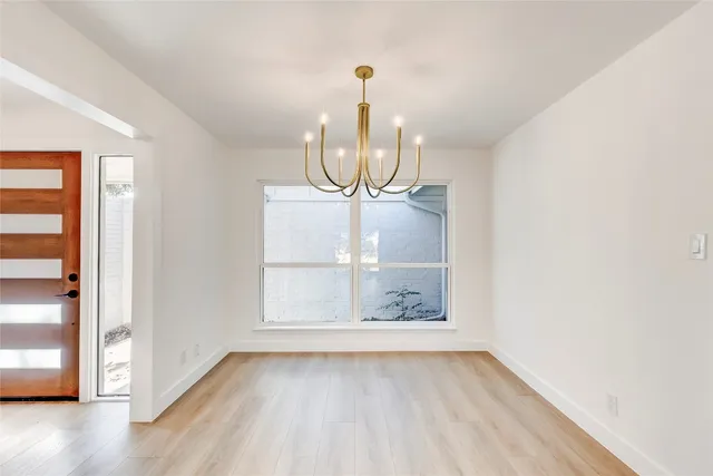 a view of a room with wooden floor chandelier and windows