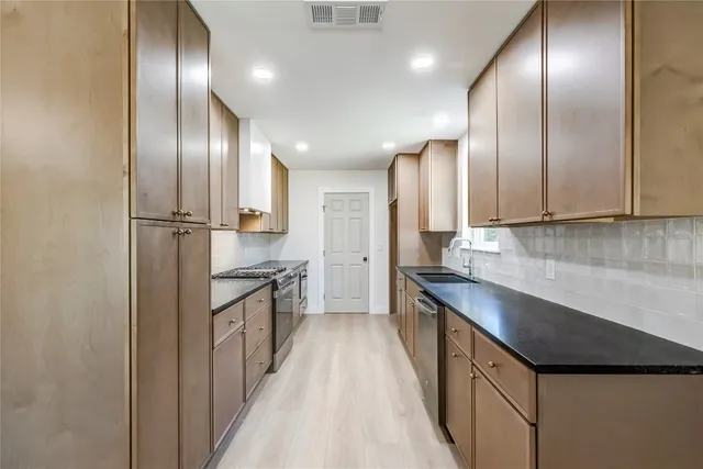 a kitchen with granite countertop stainless steel appliances cabinets a sink and a counter top space