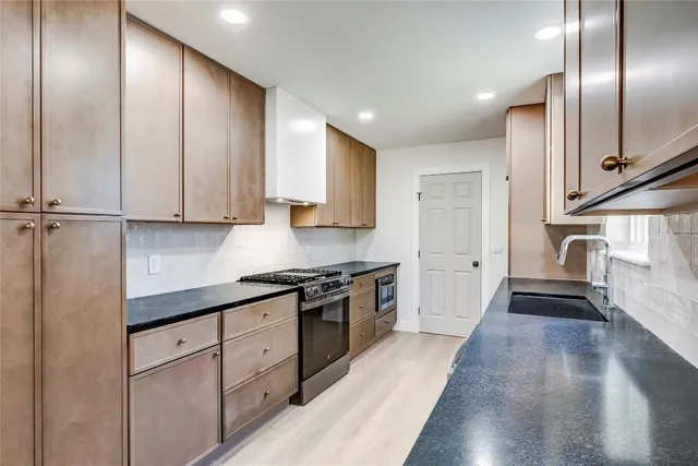 a kitchen with stainless steel appliances granite countertop a stove a sink and a refrigerator
