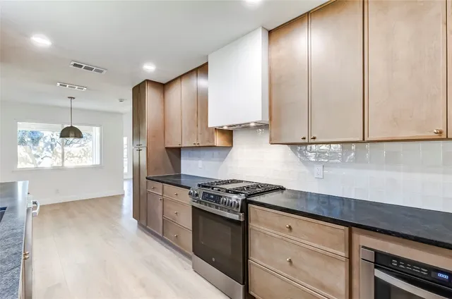 a kitchen with stainless steel appliances granite countertop a stove a sink and a refrigerator