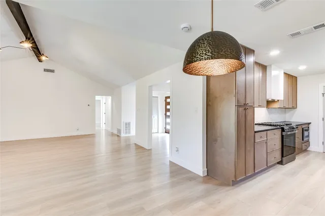 a kitchen with stainless steel appliances granite countertop a stove a refrigerator and a wooden floor