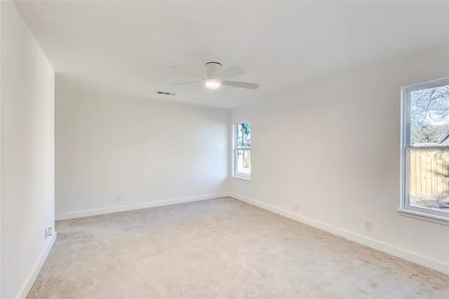 an empty room with windows and chandelier fan