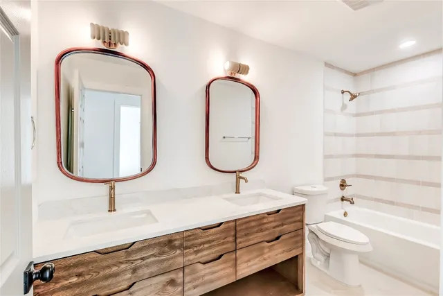 a bathroom with a double vanity sink a toilet and a bathtub