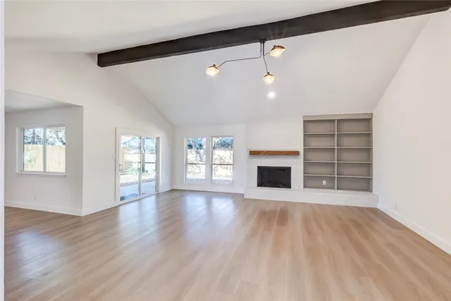 a view of an empty room with a fireplace and a window