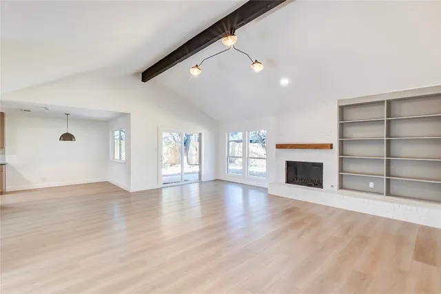 a view of an empty room with a fireplace and a window