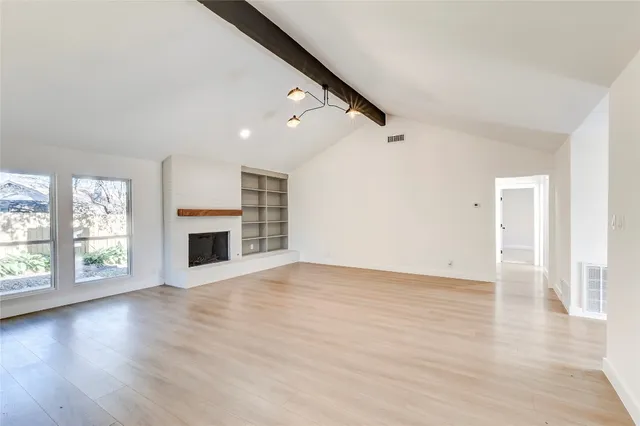 a view of empty room with wooden floor and fireplace
