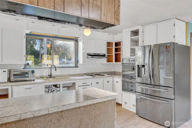 a kitchen with stainless steel appliances granite countertop a sink a stove and a refrigerator