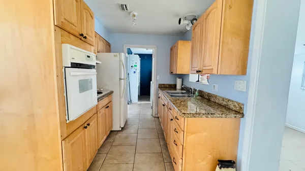 a kitchen with granite countertop a sink and refrigerator