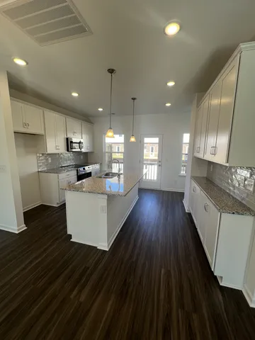a view of a kitchen counter top space a sink a center island and stainless steel appliances