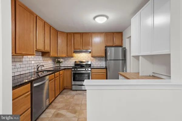 a kitchen with stainless steel appliances granite countertop a refrigerator a stove and a sink