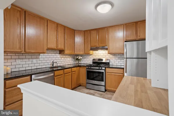 a kitchen with granite countertop stainless steel appliances and refrigerator