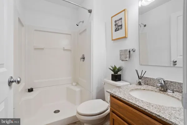 a bathroom with a granite countertop sink a toilet and shower