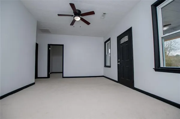 an empty room with a ceiling fan and window