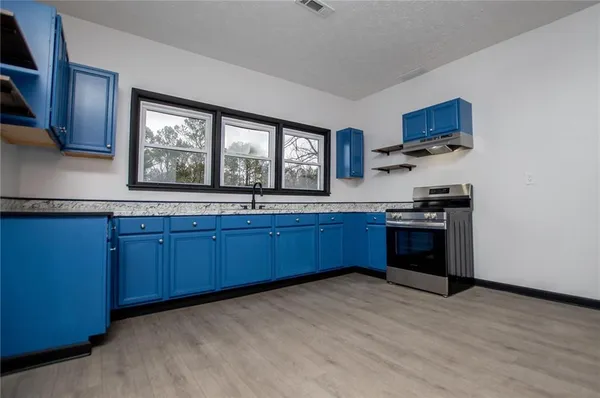 a kitchen with stainless steel appliances granite countertop a stove cabinets and a wooden floor