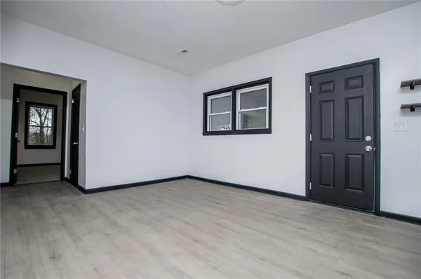 a view of an empty room with wooden floor and closet