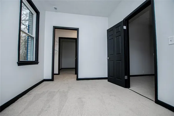 a view of an empty room with closet and a window
