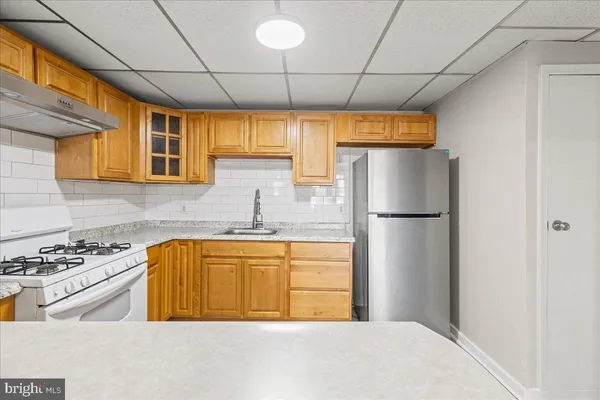 a kitchen with stainless steel appliances granite countertop a refrigerator a sink dishwasher a stove with wooden cabinets