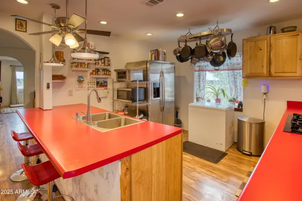 a view of a kitchen with kitchen island stainless steel appliances wooden floor and living room view