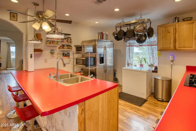 a view of a kitchen with kitchen island stainless steel appliances wooden floor and living room view