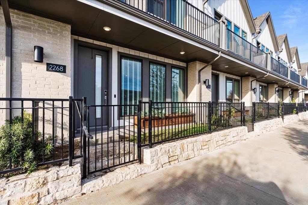2268 Rook Drive Dallas, TX 75211 - Photo 11 of 13 The property features a stone and brick exterior, a gated front yard, and a balcony