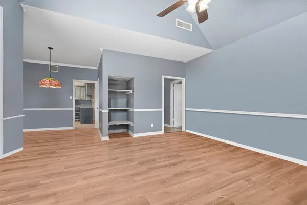 a view of empty room with wooden floor fan and window