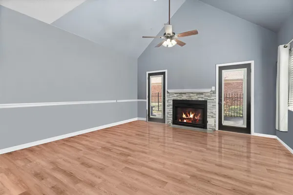 a view of an empty room with wooden floor fireplace and a window