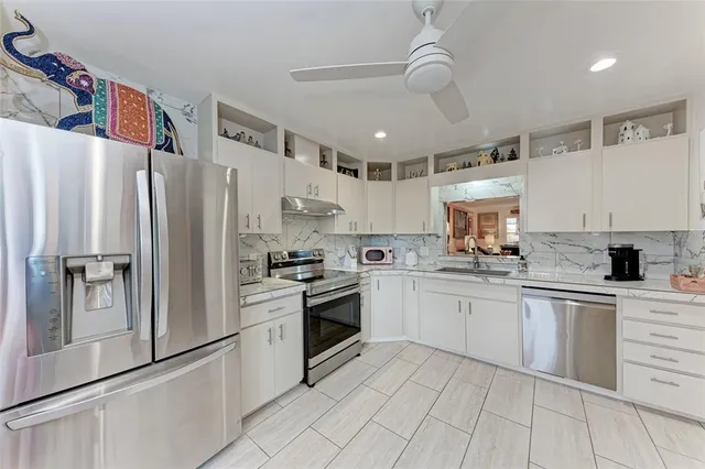 a kitchen with granite countertop a refrigerator and a stove top oven