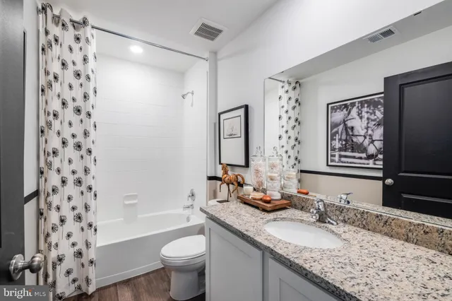 a bathroom with a granite countertop sink a toilet and a large mirror