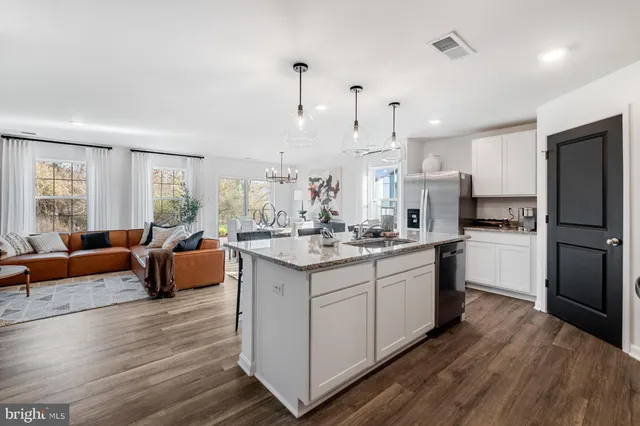 a kitchen with stainless steel appliances granite countertop a refrigerator a sink dishwasher a stove and white countertops with wooden floor