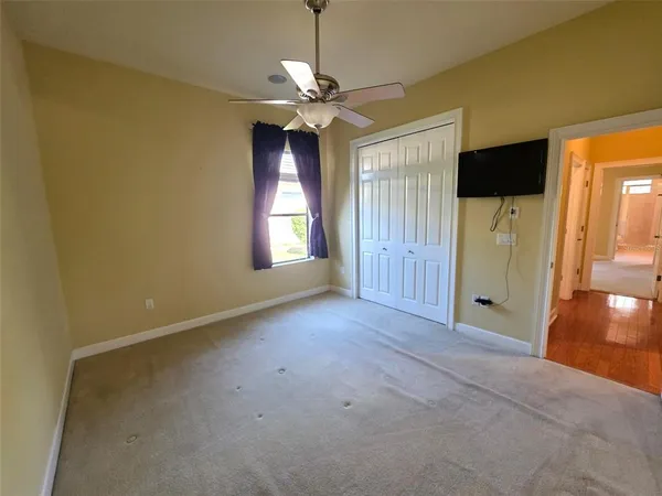 an empty room with windows and chandelier fan