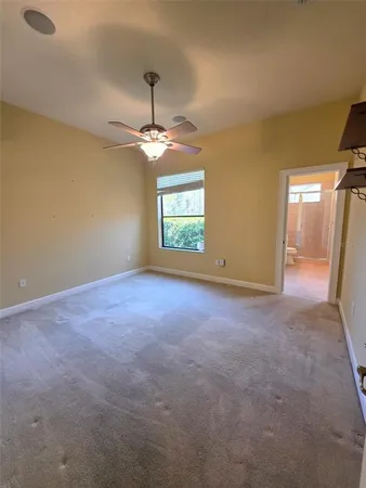 an empty room with windows and chandelier fan