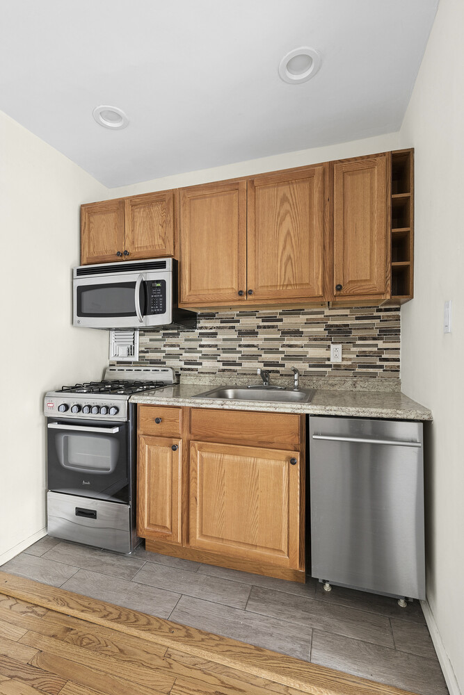 1420 York Avenue, Unit 4B Manhattan, NY 10021 - Photo 3 of 9 a kitchen with stainless steel appliances granite countertop a stove a sink and a microwave