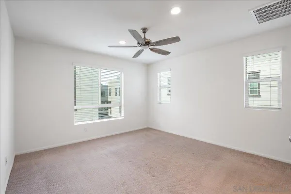an empty room with windows and fan