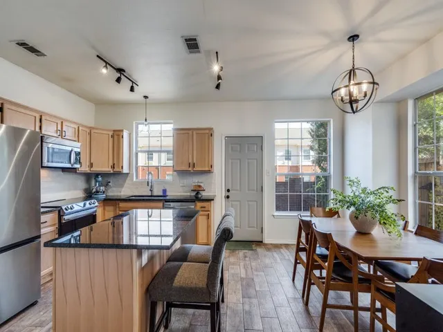 a kitchen with granite countertop stainless steel appliances a table and chairs in it