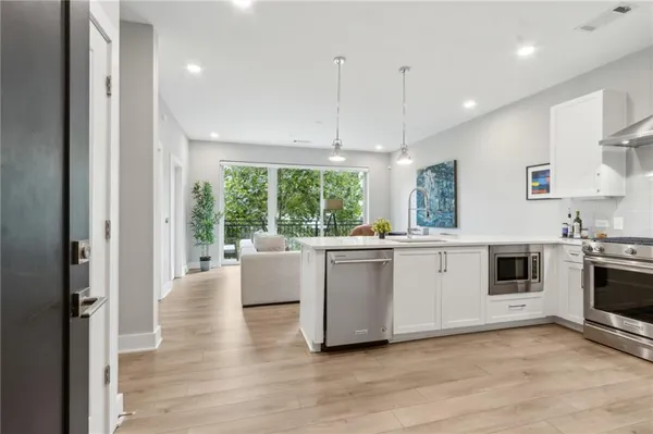 a kitchen with stainless steel appliances granite countertop a stove a sink and white cabinets with wooden floors