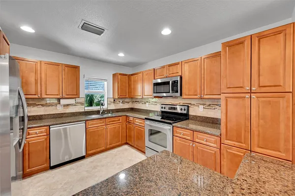 a kitchen with granite countertop wooden cabinets stainless steel appliances and a window